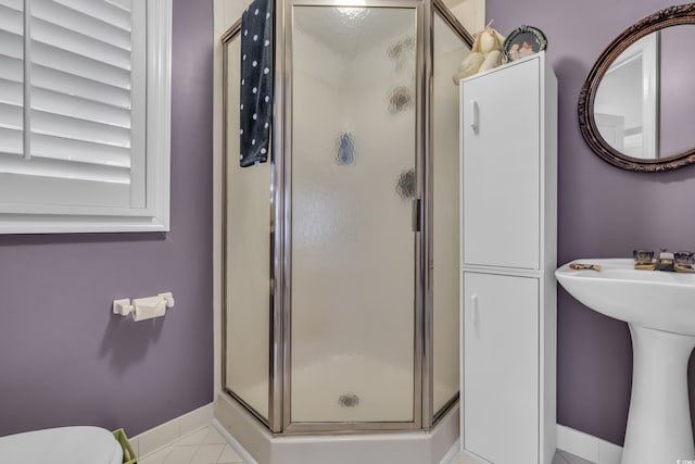 full bathroom with toilet, a shower stall, baseboards, and tile patterned floors