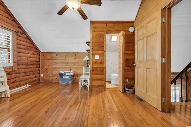 additional living space featuring visible vents, a ceiling fan, vaulted ceiling, log walls, and light wood finished floors