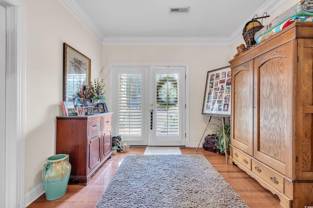 doorway featuring visible vents, crown molding, and baseboards