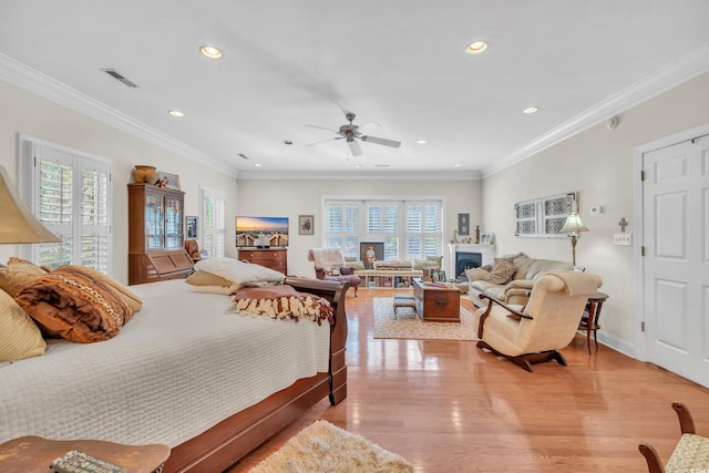 bedroom with visible vents, light wood-style flooring, ornamental molding, a fireplace, and recessed lighting