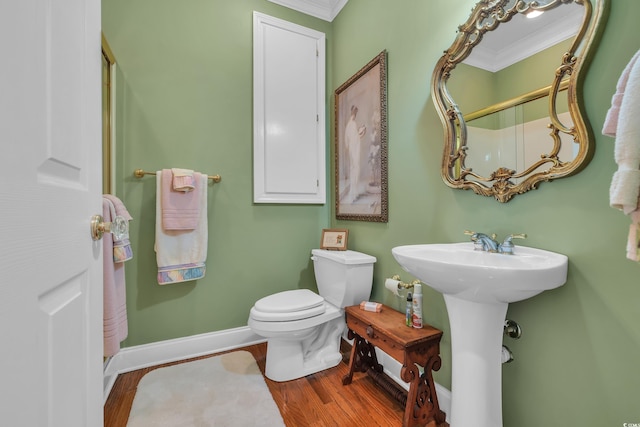 bathroom featuring toilet, ornamental molding, a sink, wood finished floors, and baseboards