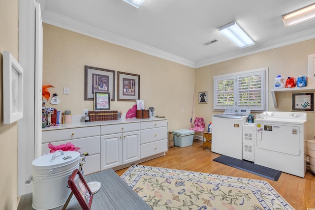 clothes washing area featuring crown molding, light wood finished floors, visible vents, cabinet space, and washer and dryer