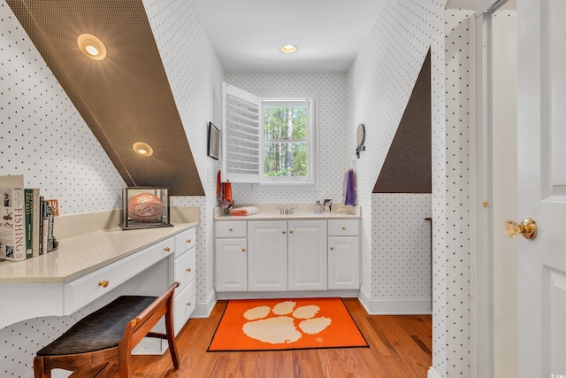 kitchen featuring light wood-style floors, light countertops, white cabinets, and wallpapered walls