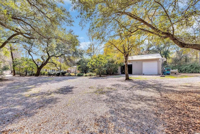 view of yard with a garage, an outbuilding, and driveway