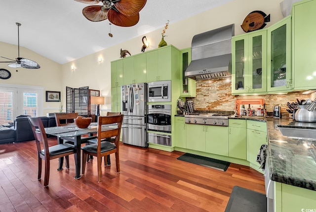 kitchen featuring dark wood-style floors, stainless steel appliances, wall chimney range hood, and a ceiling fan