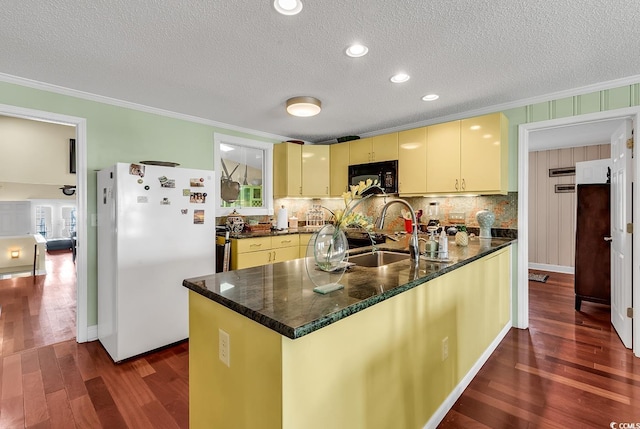 kitchen featuring freestanding refrigerator, black microwave, a sink, and cream cabinets