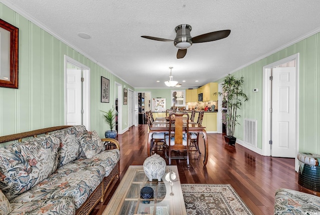 living area with dark wood-style flooring, visible vents, and crown molding