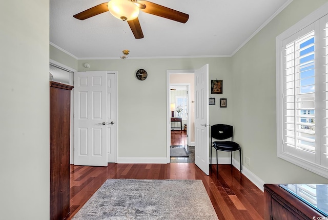 interior space featuring a ceiling fan, crown molding, baseboards, and dark wood-style flooring