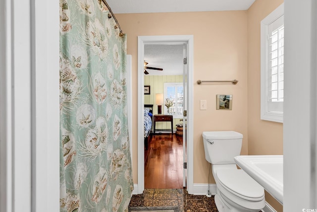 bathroom with a healthy amount of sunlight, baseboards, and toilet