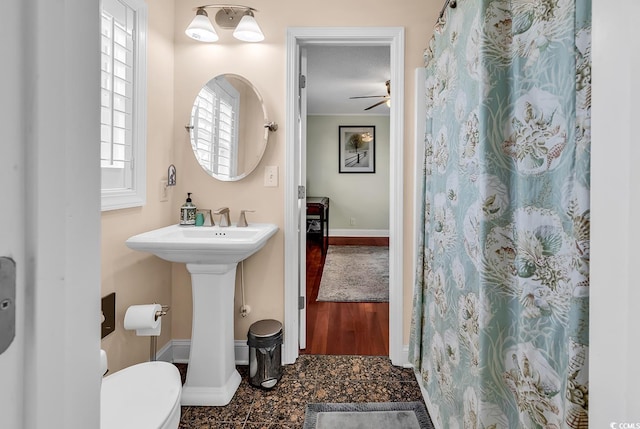 full bath with baseboards, toilet, ceiling fan, granite finish floor, and a sink