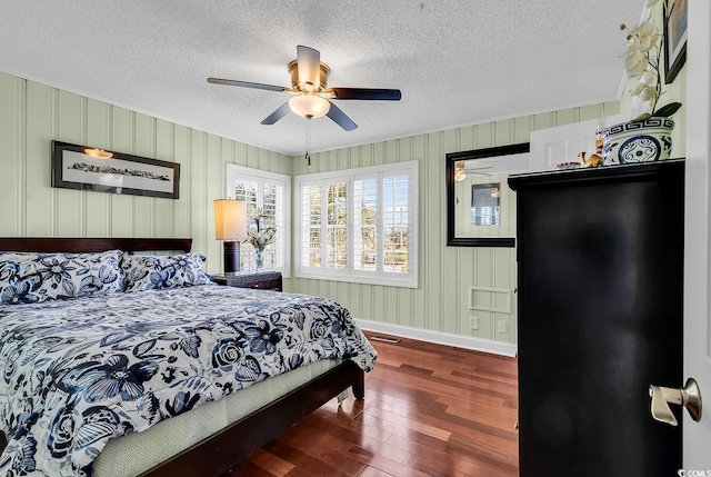 bedroom with a textured ceiling, ceiling fan, wood finished floors, visible vents, and baseboards