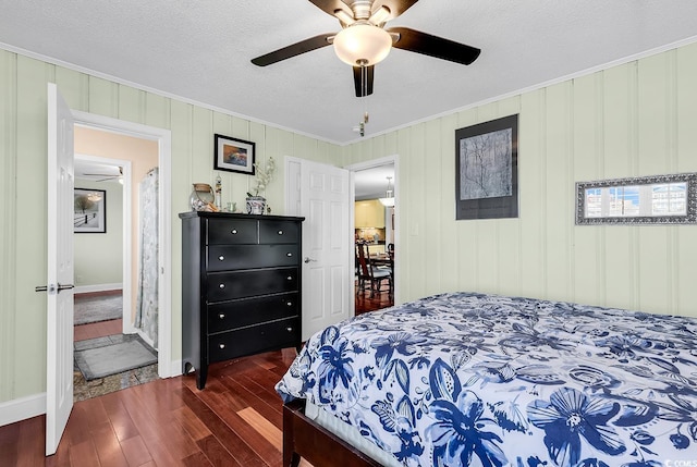 bedroom featuring dark wood-style floors, ornamental molding, a textured ceiling, and a ceiling fan