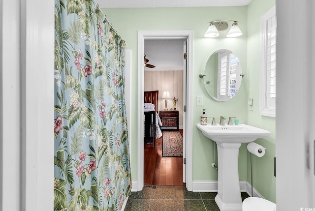 ensuite bathroom with connected bathroom, a shower with shower curtain, a sink, granite finish floor, and baseboards