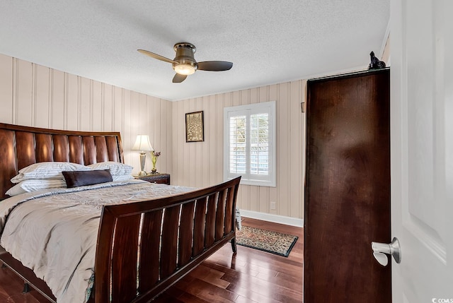 bedroom featuring a ceiling fan, dark wood-style flooring, a textured ceiling, and baseboards