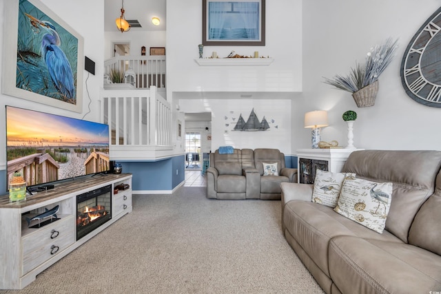 living area featuring a glass covered fireplace, baseboards, a high ceiling, and speckled floor