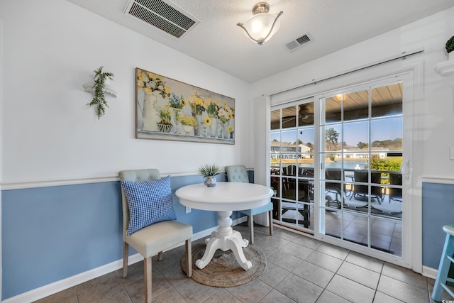 dining room with visible vents, a textured ceiling, baseboards, and tile patterned floors