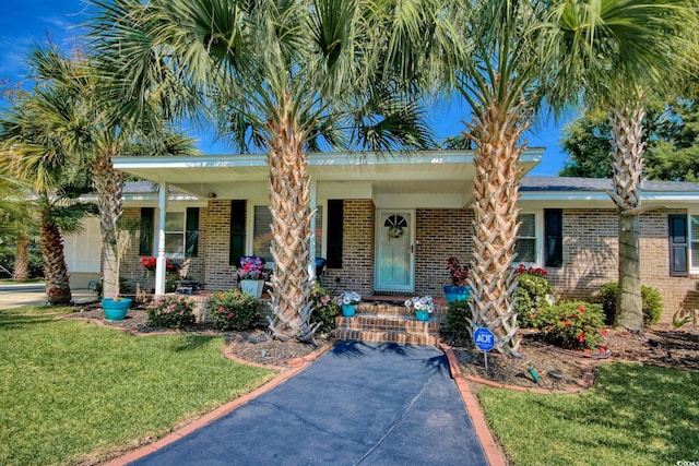 view of front facade featuring covered porch, brick siding, and a front lawn