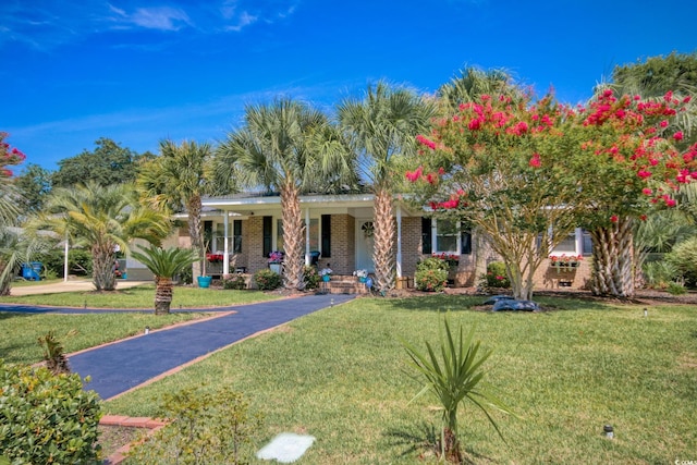 single story home with covered porch, a front lawn, and brick siding