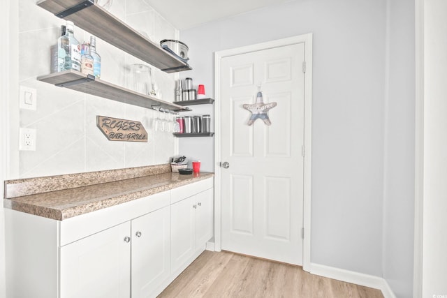 interior space with light wood-type flooring, tasteful backsplash, white cabinetry, and open shelves
