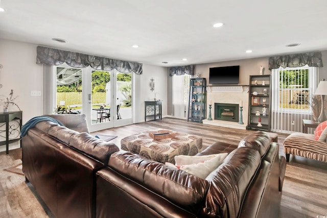 living area with recessed lighting, a fireplace with raised hearth, plenty of natural light, and wood finished floors