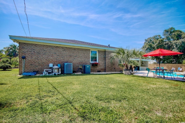 back of property featuring a yard, brick siding, a patio, and crawl space
