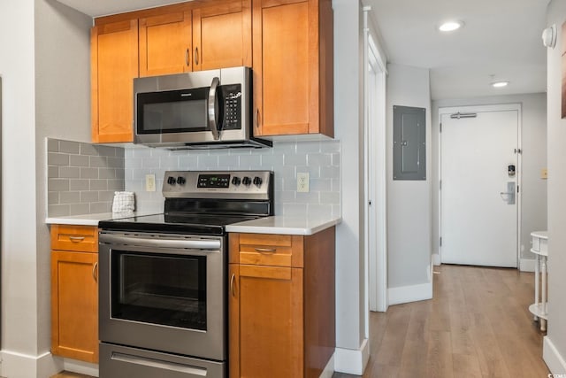 kitchen featuring light wood finished floors, light countertops, appliances with stainless steel finishes, and electric panel