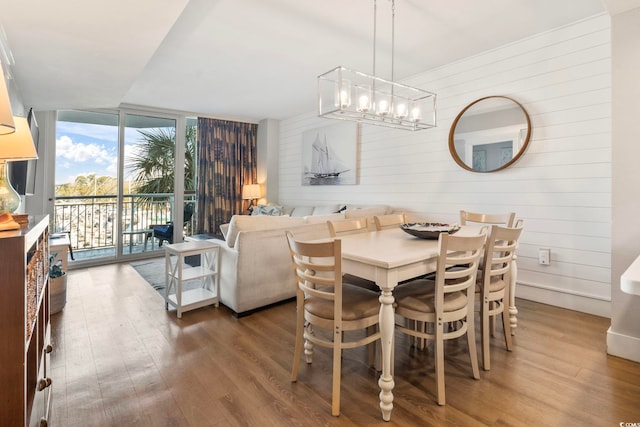 dining room with a chandelier, expansive windows, and wood finished floors