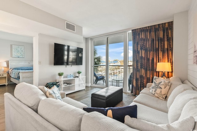 living area with a wall of windows, wood finished floors, and visible vents