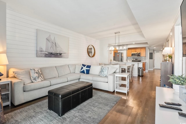 living area featuring a chandelier, recessed lighting, dark wood finished floors, and wood walls