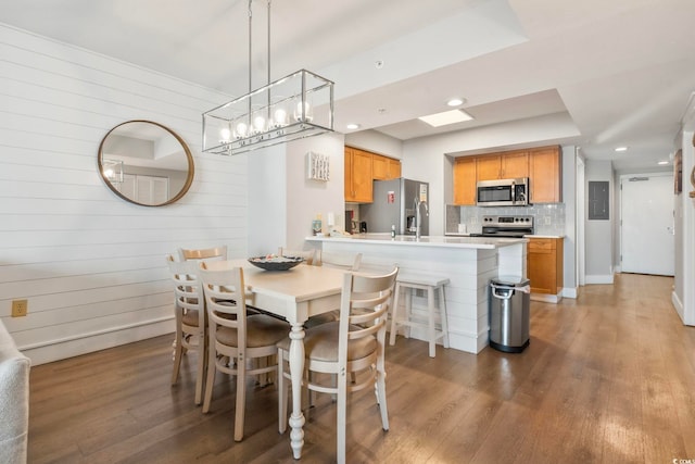 dining area with recessed lighting, electric panel, wood walls, and wood finished floors