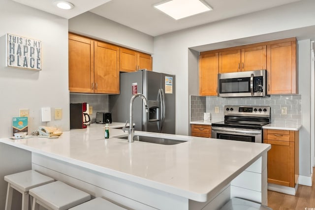 kitchen with stainless steel appliances, a peninsula, light countertops, and brown cabinets