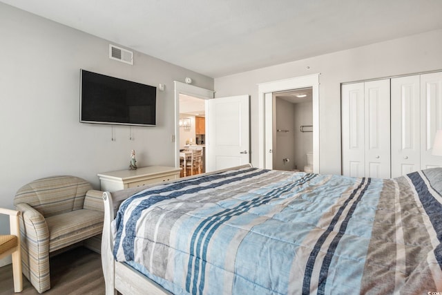 bedroom with a closet, wood finished floors, and visible vents