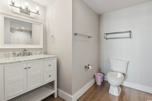 bathroom featuring vanity, wood finished floors, toilet, and baseboards