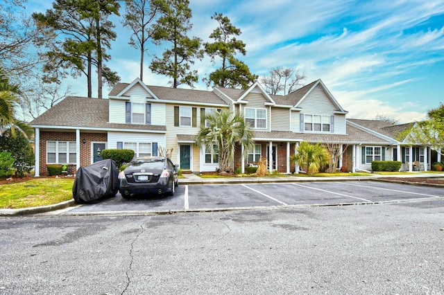 view of property featuring uncovered parking and brick siding