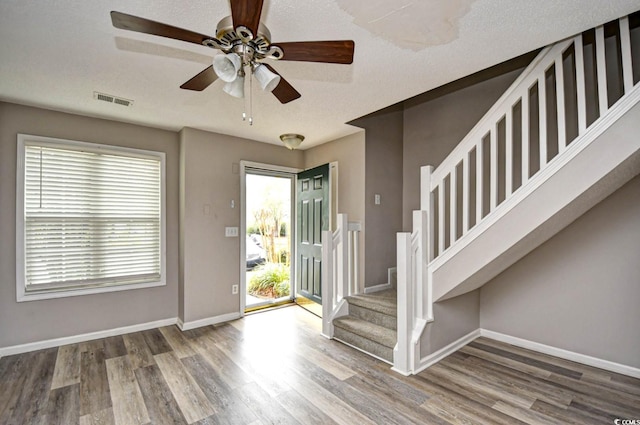 entryway with stairway, wood finished floors, visible vents, and baseboards