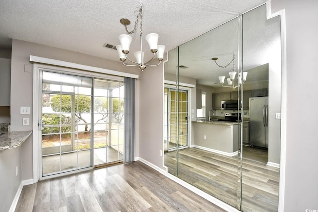 interior space featuring visible vents, stainless steel appliances, a notable chandelier, and wood finished floors