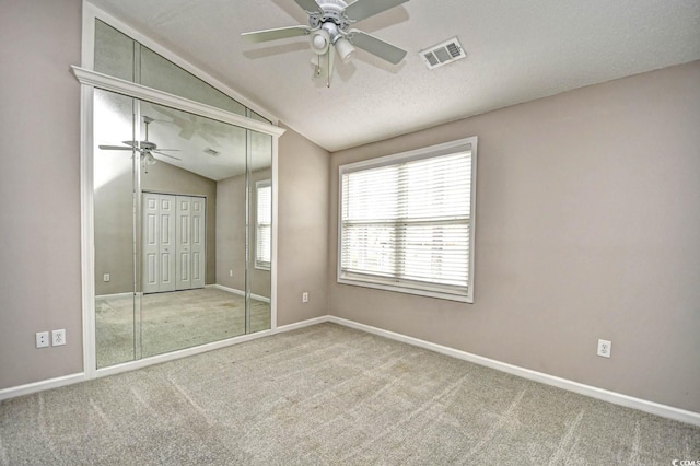 unfurnished bedroom featuring lofted ceiling, carpet flooring, visible vents, and baseboards