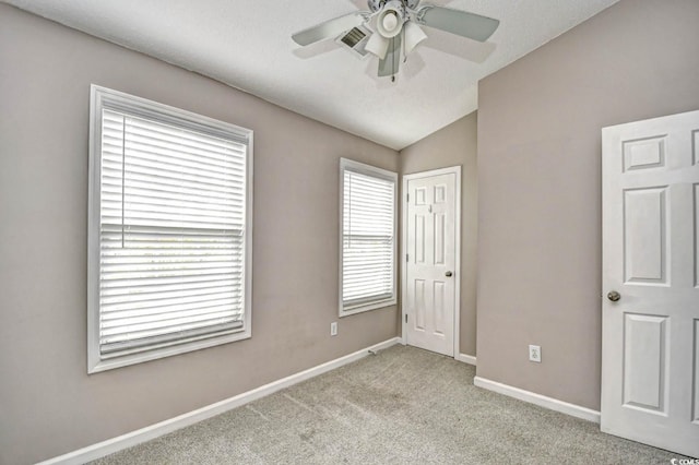 unfurnished bedroom featuring carpet, lofted ceiling, visible vents, a ceiling fan, and baseboards