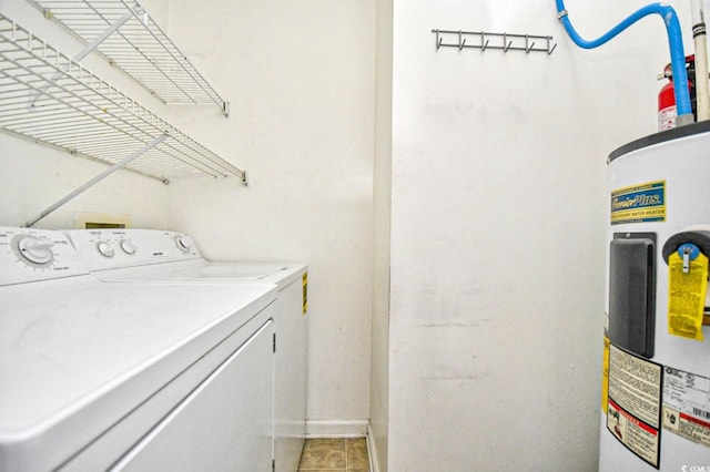 laundry area with laundry area, water heater, washing machine and clothes dryer, and light tile patterned floors