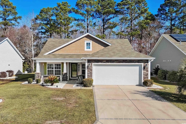 craftsman house with concrete driveway, stone siding, a front lawn, and an attached garage