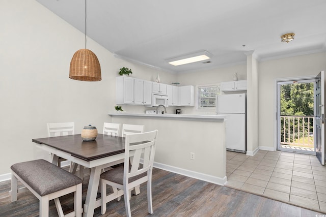 dining space with light wood-type flooring, baseboards, and ornamental molding