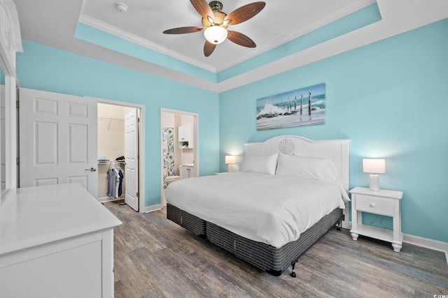 bedroom with baseboards, a raised ceiling, and wood finished floors