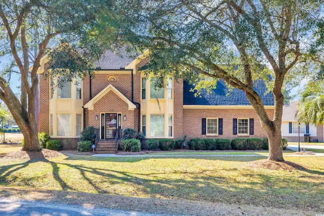 view of front of property featuring a shingled roof, a front lawn, and brick siding