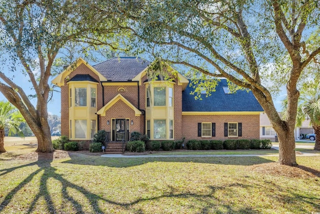 view of front of home featuring brick siding, a front yard, and a shingled roof