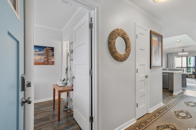 hallway featuring visible vents, crown molding, baseboards, and wood finished floors