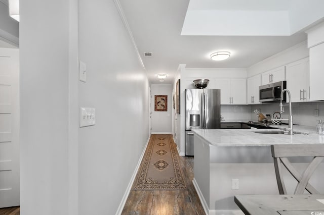 kitchen with visible vents, decorative backsplash, appliances with stainless steel finishes, white cabinetry, and a sink