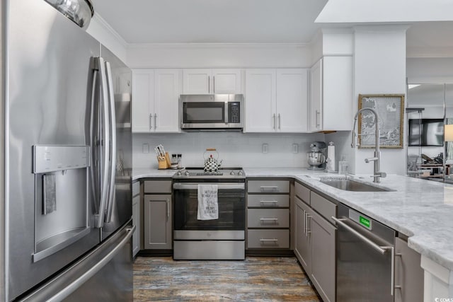 kitchen with gray cabinetry, stainless steel appliances, a sink, ornamental molding, and tasteful backsplash