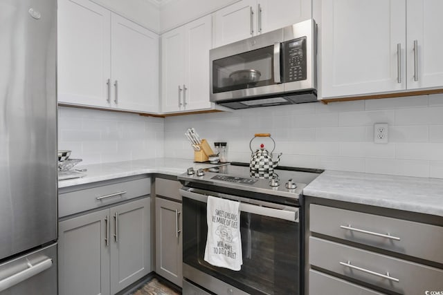 kitchen featuring stainless steel appliances, light countertops, decorative backsplash, and gray cabinetry