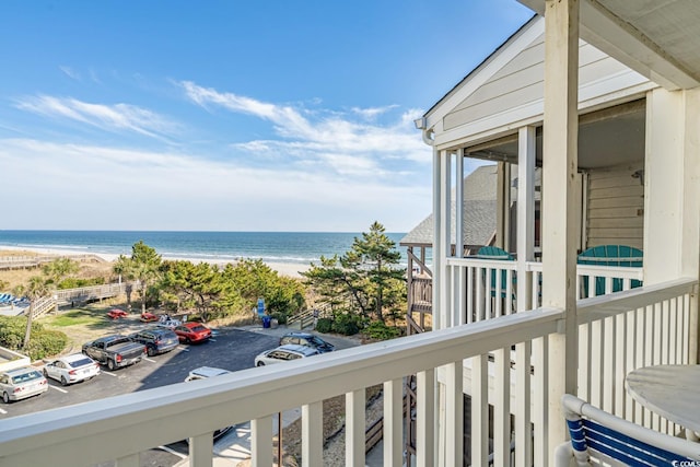 balcony with a water view and a view of the beach