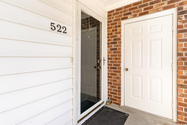 doorway to property featuring a garage and brick siding